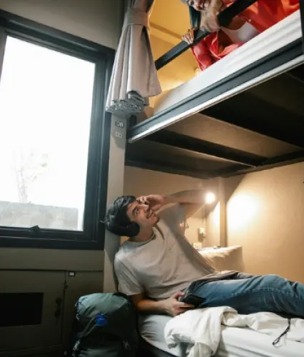 Man on bunk bed smiling in cozy, friendly room
