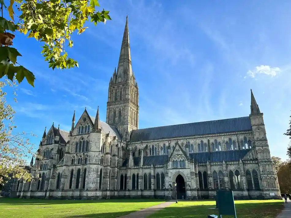 Salisbury Cathedral with its soaring spire rising above green cathedral lawns