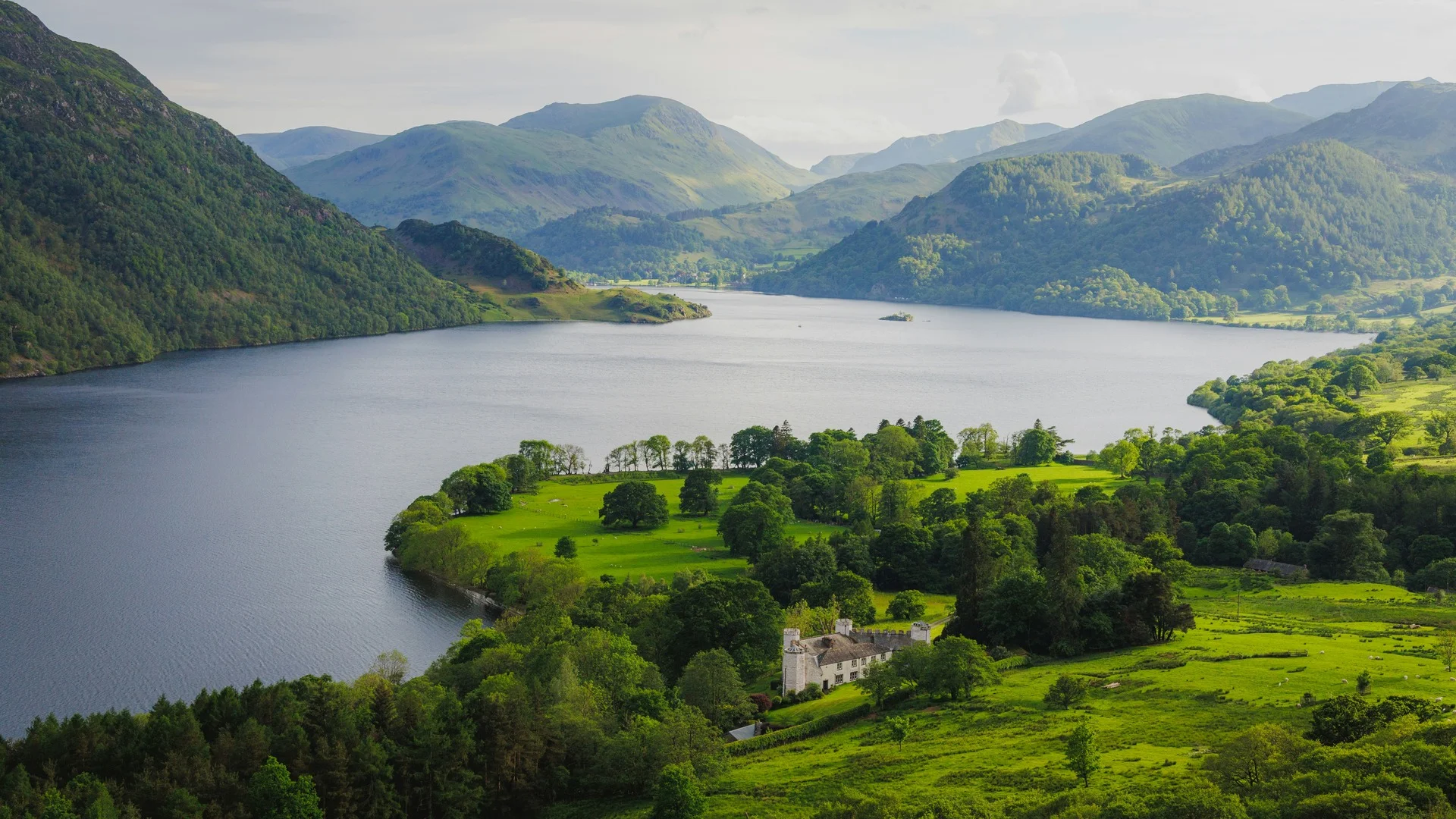 A serene lake nestled between green hills in the picturesque Lake District of England.