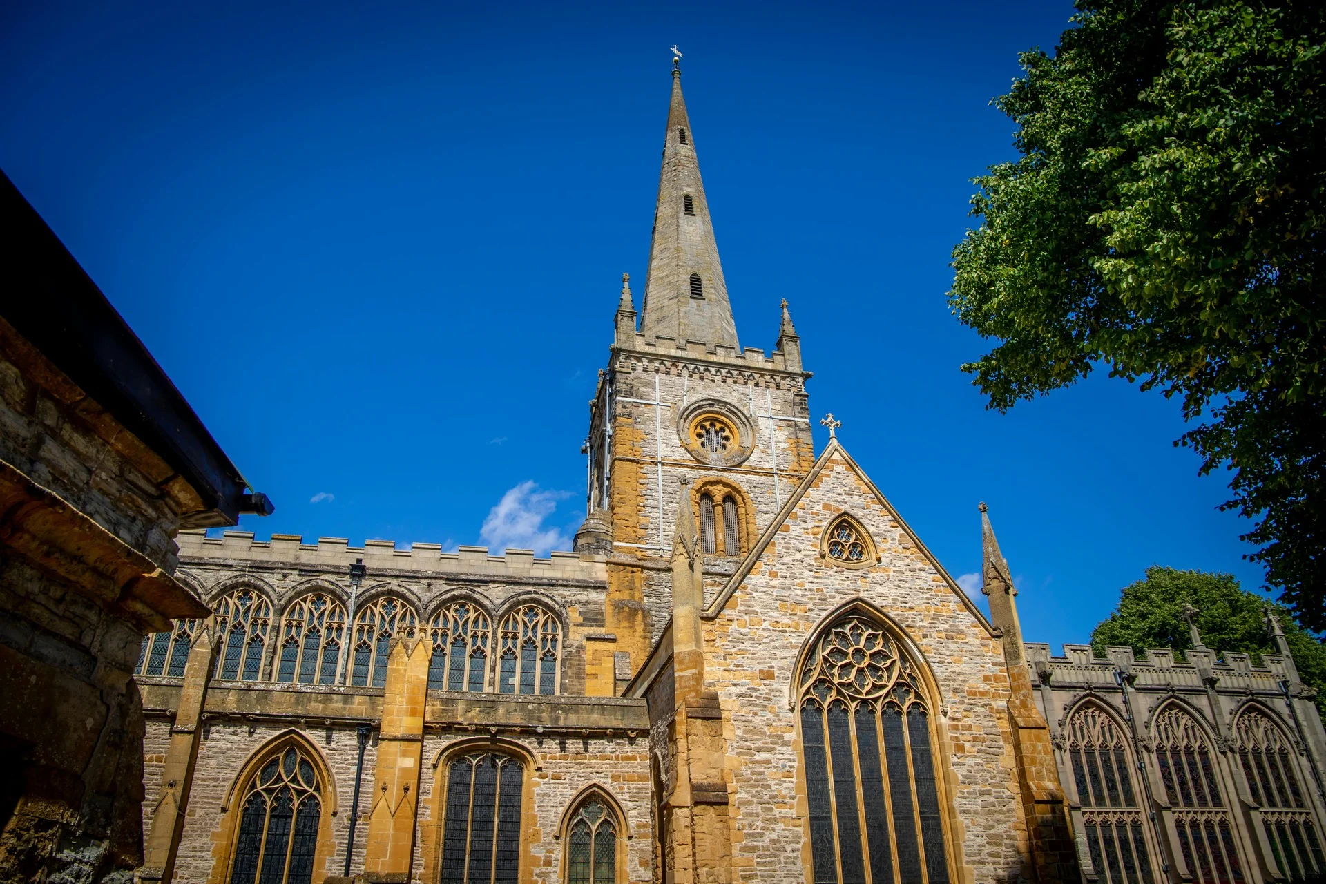 The impressive exterior of Holy Trinity Church in Stratford-upon-Avon against a bright blue sky.
