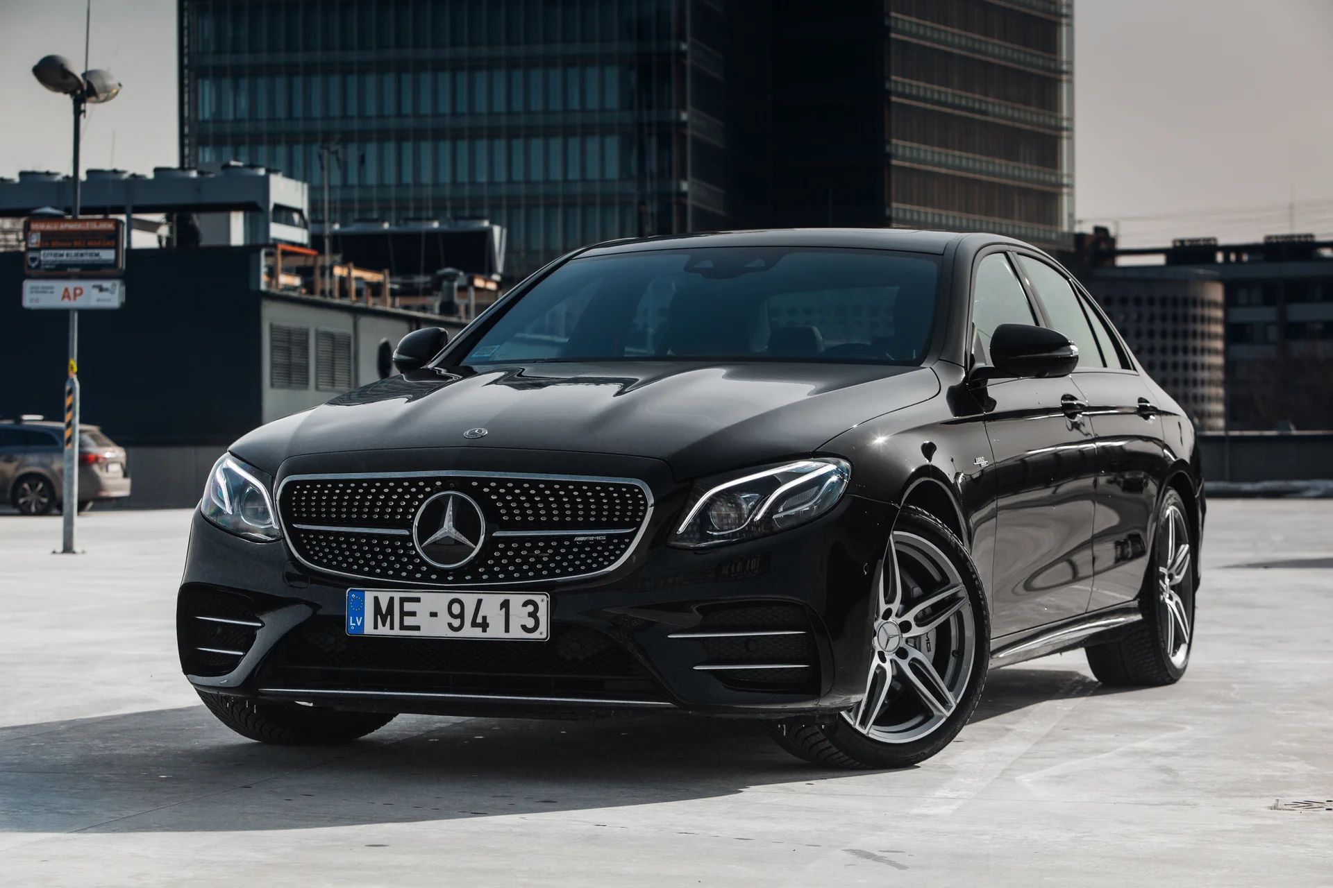 Black Mercedes-Benz sedan parked in an urban lot with buildings in the background.