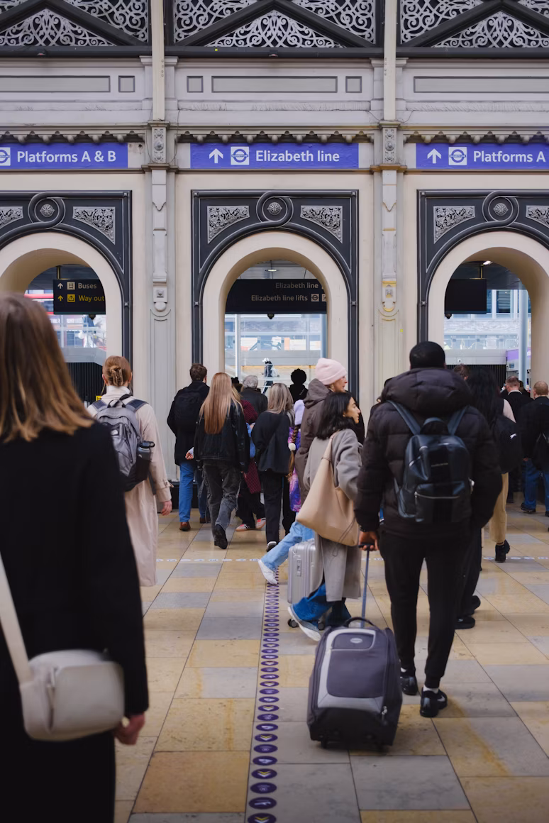 Travelers with luggage crossing a grand historic railway station concourse in Britain