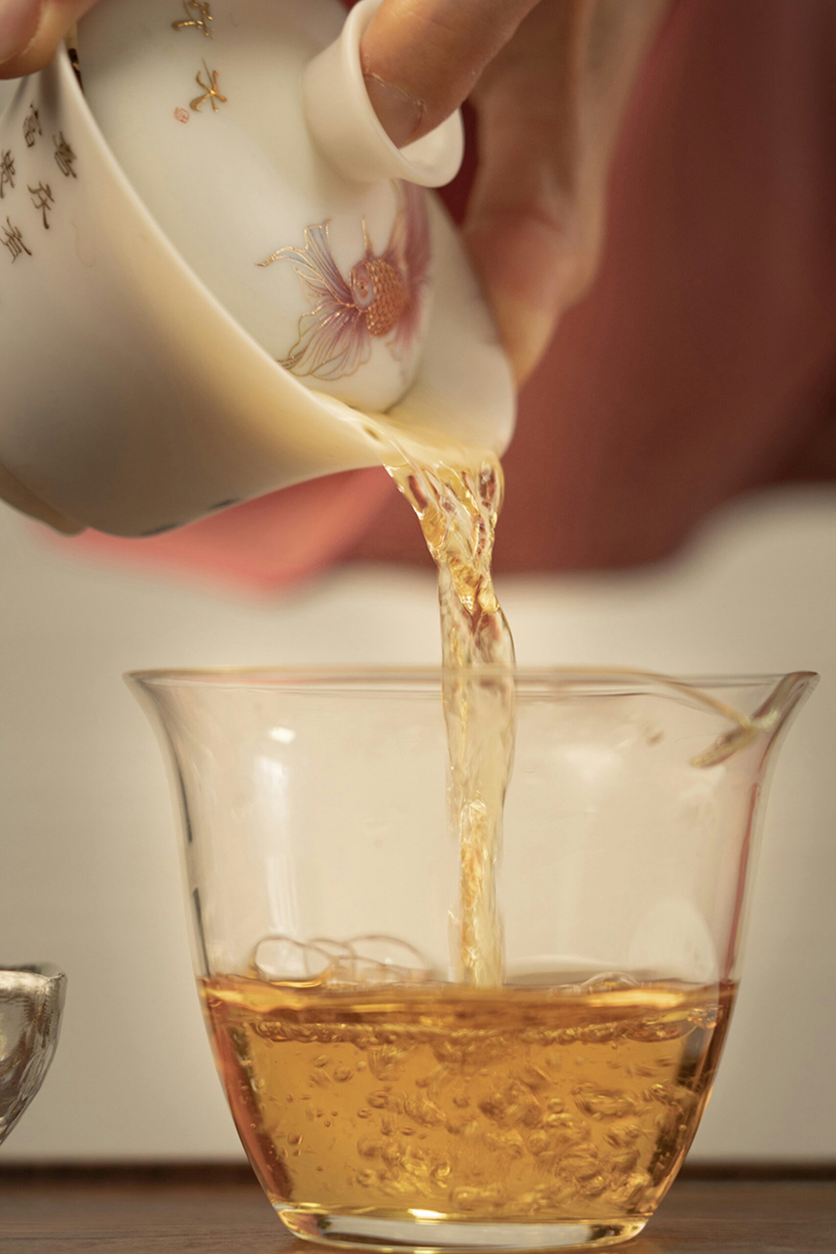 Freshly brewed British tea being poured into an elegant fine china teacup during a traditional afternoon tea experience.