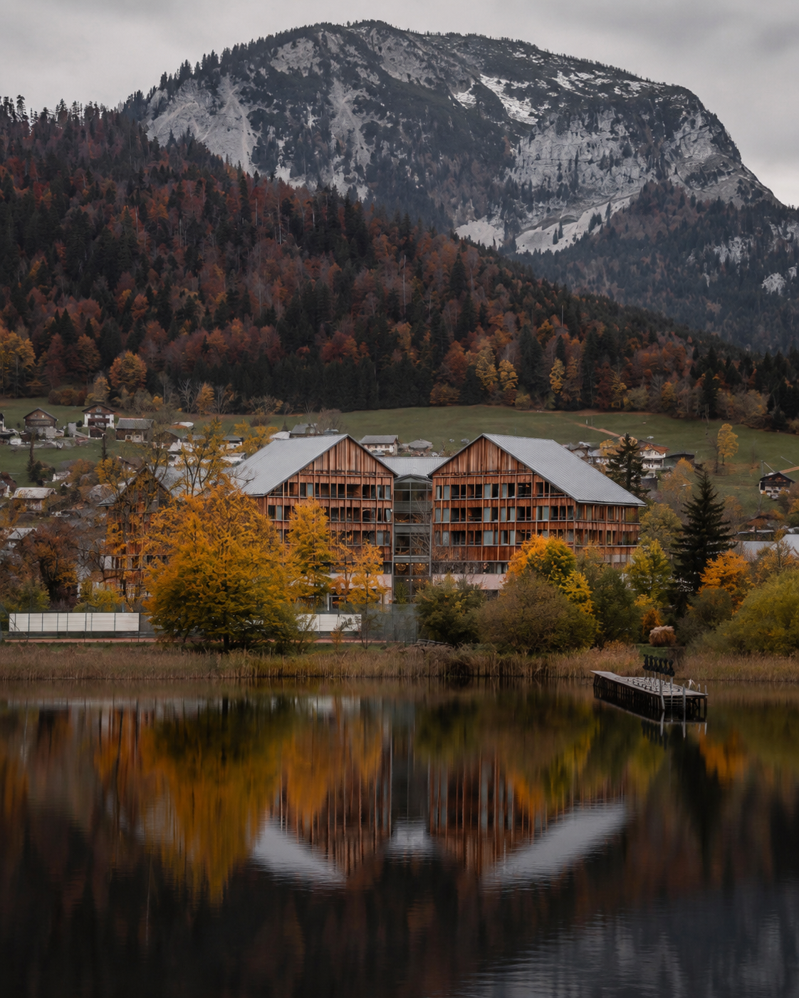 Lakeside cottages beneath snow-capped mountains in the Lake District in autumn