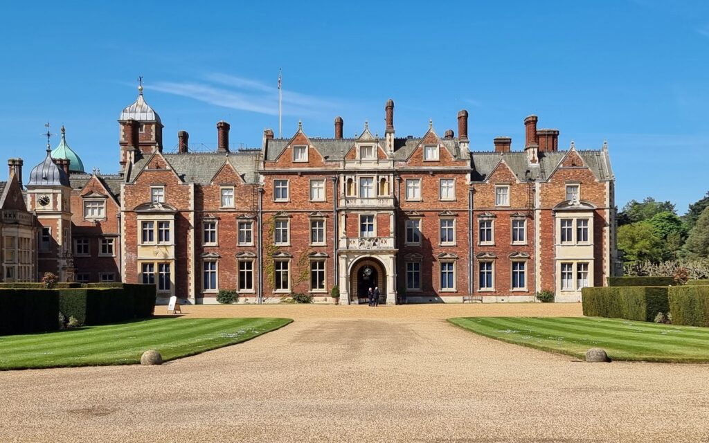 Sandringham House red brick facade in Norfolk, viewed along the estate driveway