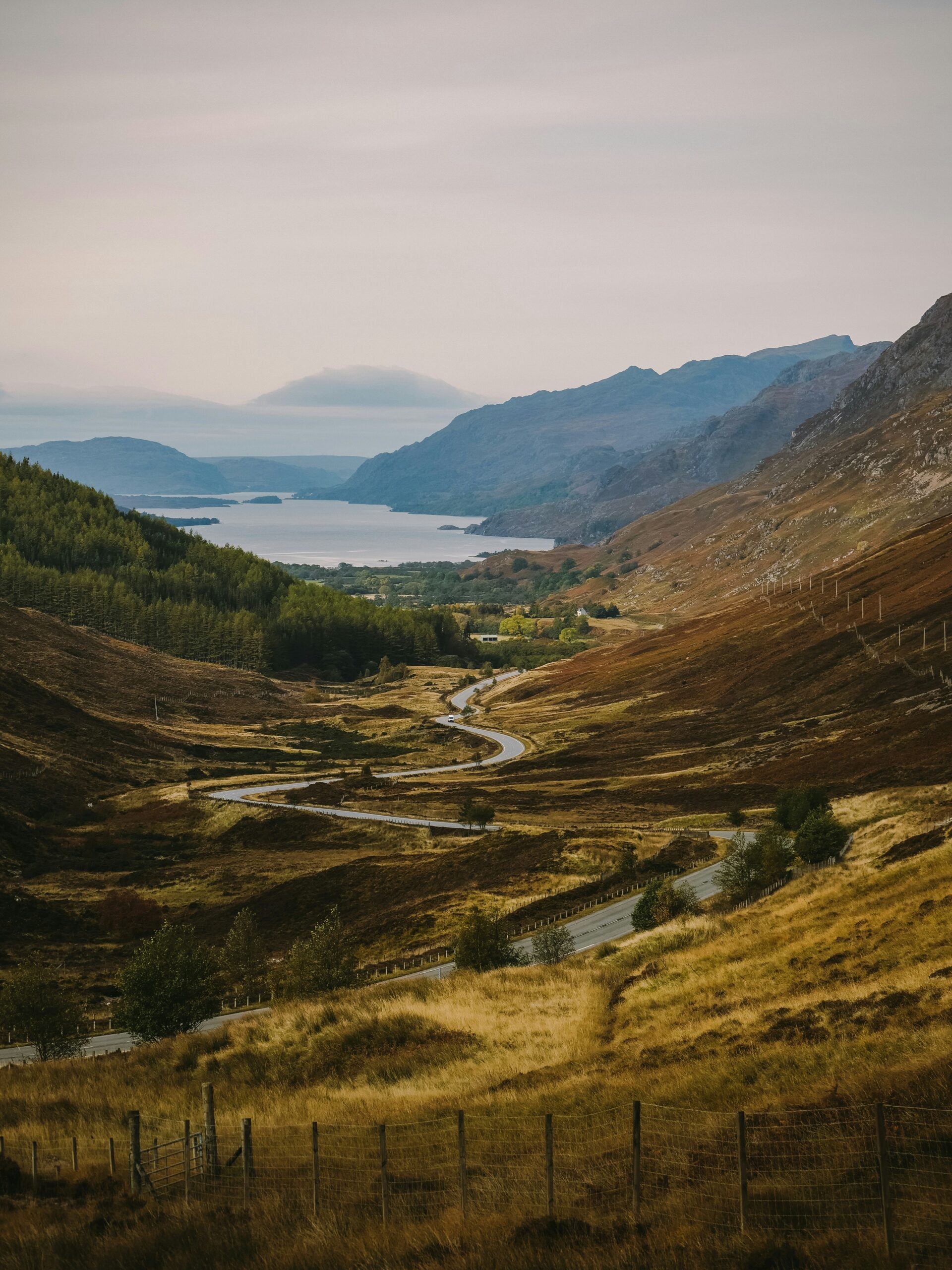 Winding road beside a Scottish loch surrounded by autumn hills and mountains