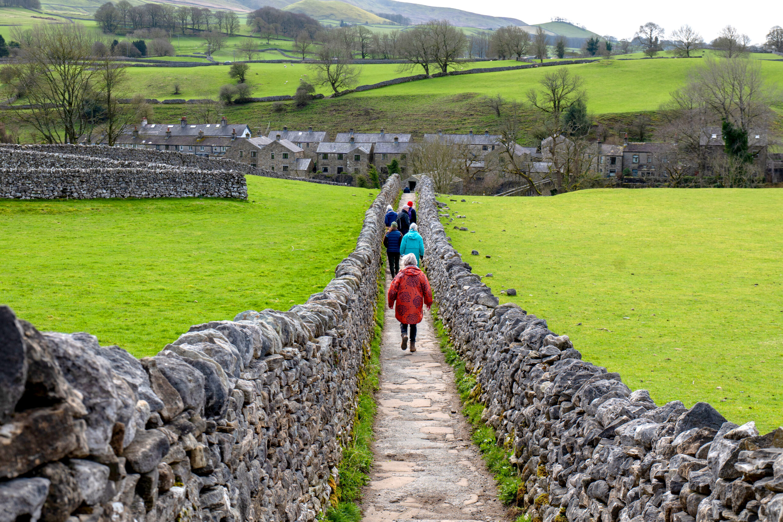 Walkers on a stone footpath between dry stone walls in the Yorkshire Dales